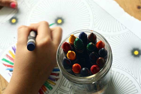 Child colouring in a colouring book using crayons