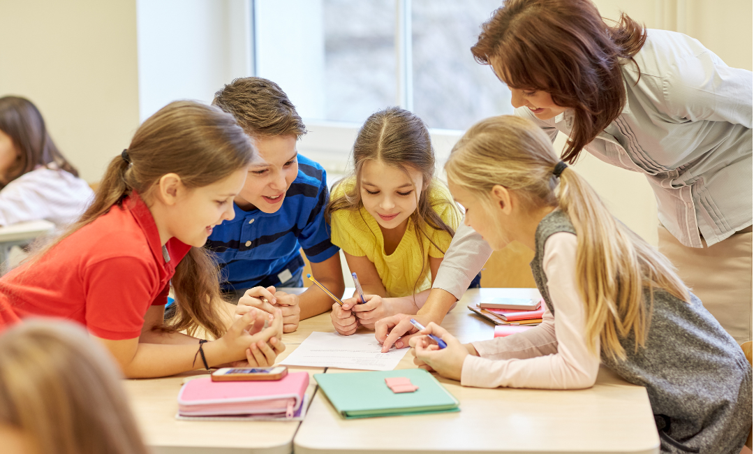 A teacher working with a group of young students on a project